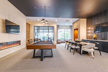 A room with a pool table, a fireplace, and a dining table